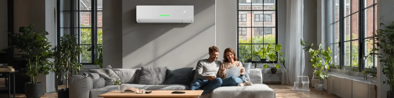 Pompe à chaleur réversible en fonctionnement dans un salon, montrant les flux d'air chaud et froid selon la saison.
